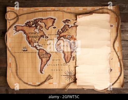 Vintage pirate map and blank sheet of papyrus with place for text on a round wooden table Stock Photo