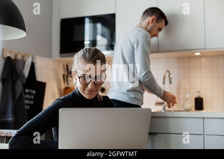 Woman in kitchen using laptop Stock Photo
