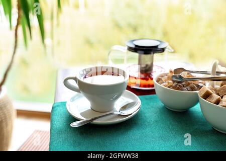 Red herbal tea with cranberries in ceramic white cup with white and cane sugar on blue tablecloth. Food background with copy space. Food and drink concept. Stock Photo