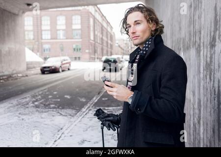 Young man in winter clothing holding phone Stock Photo