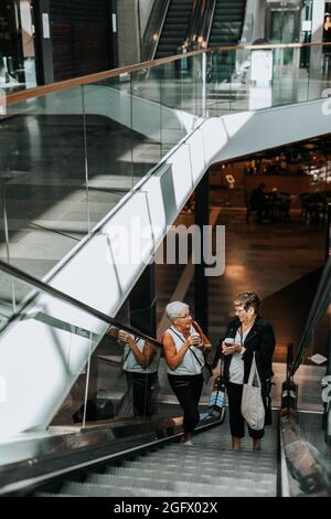 Senior women standing on escalator Stock Photo