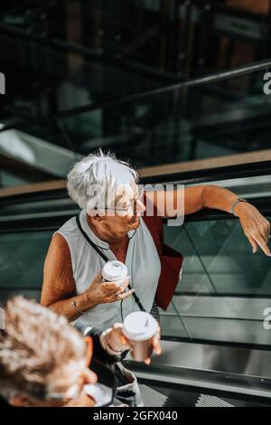 Senior woman standing on escalator Stock Photo