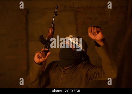 Happy Islamic militant or soldier with face cover dancing with gun in hand for victory in war Stock Photo
