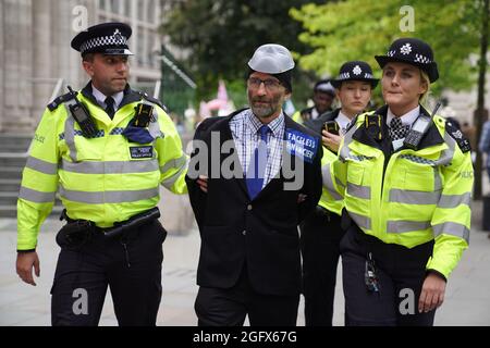 A protester is detained by police officers as an Extinction Rebellion protest makes its way through the City of London. Picture date: Friday August 27, 2021. Stock Photo