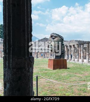 Vertical shot of damaged bust by ancient bricks in ruins of pompeii, italy Stock Photo
