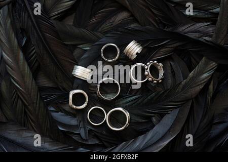 Above view of beautiful handmade silver rings placed on black feathers, jewelry store Stock Photo