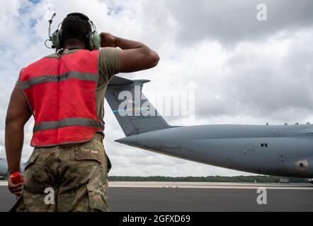 Senior Airman Deondre Douglas, 512th Maintenance Squadron, salutes a C-5M Super Galaxy as it taxis before taking off to Hamid Karzai International Airport, Afghanistan from Dover Air Force Base, Delaware, Aug. 16, 2021. Air Mobility Airmen play a key role in facilitating the safe departure and relocation of U.S. citizens, Special Immigration Visa recipients, and vulnerable Afghan populations from Afghanistan. (U.S. Air Force photo by Senior Airman Faith Schaefer) Stock Photo