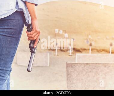 Gun in the hands of a girl, close-up arms. Stock Photo