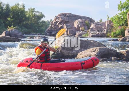 A man rowing inflatable packraft on whitewater of mountain river. Concept: summer extreme water sport,  active rest, extreme rafting. Stock Photo
