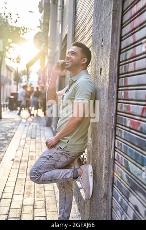 Latin man leaning against the wall talking on his cell phone. Portrait in backlight. Concept of communication. . High quality photo Stock Photo
