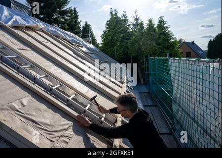 Roofer fixing new insulation on the roof of a old house. Stock Photo