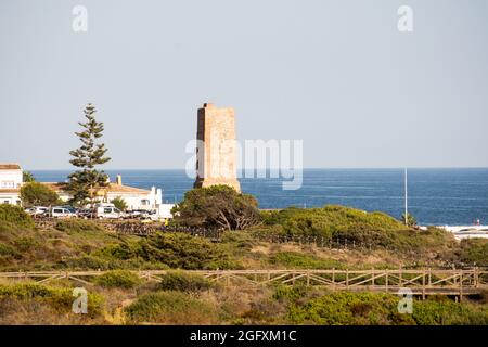 Wooden walkway at protected dune vegetation with the Moorish lookout tower, Thieves Tower, at beach Cabopino near Marbella, Andalusia, Spain. Stock Photo