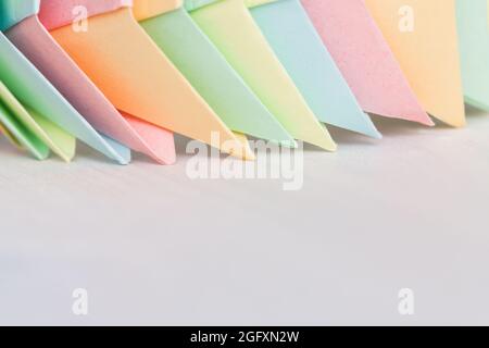 Origami, colorful structure made of colorful paper sheets lays on a white wooden desk Stock Photo