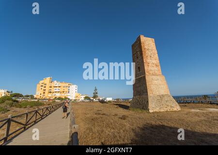 Wooden walkway at protected dune vegetation with the Moorish lookout tower, Thieves Tower, at beach Cabopino near Marbella, Andalusia, Spain. Stock Photo