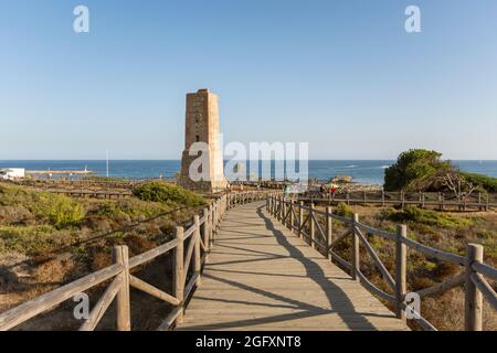 Wooden walkway at protected dune vegetation with the Moorish lookout tower, Thieves Tower, at beach Cabopino near Marbella, Andalusia, Spain. Stock Photo