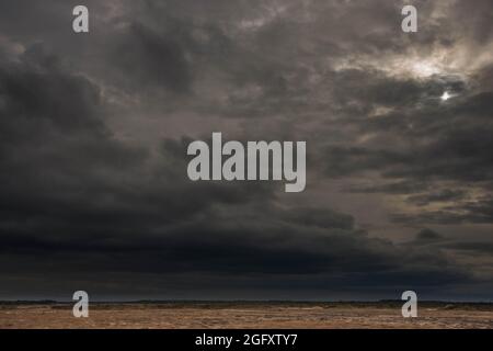A vast plain covered with arable fields and meadows. The sky is overcast, covered with dark, awe-inspiring clouds that herald the impending downpour. Stock Photo