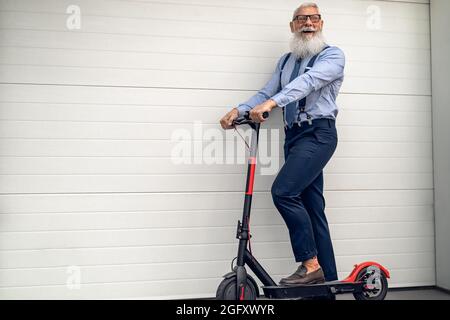 Business senior man going to work in office with electric scooter - Eco transport concept Stock Photo