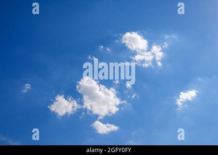 Some fluffy white clouds on a deep blue sky in summer Stock Photo