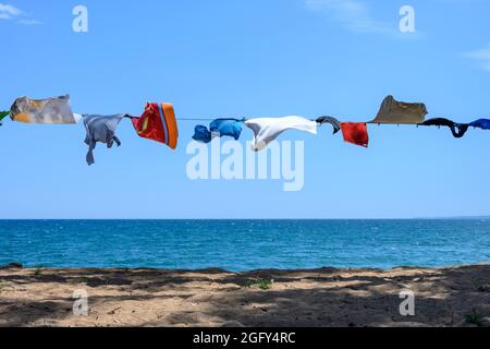 Campers clothes on a washing line next to the sea on a beach in Southern Greece. Stock Photo