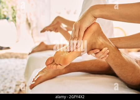 Couple getting foot massage at wellness center during romantic vacation. Foot reflexology, foot massage with oil, close-up Stock Photo