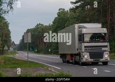 Close-up of a white truck on an asphalt road in the forest Stock Photo