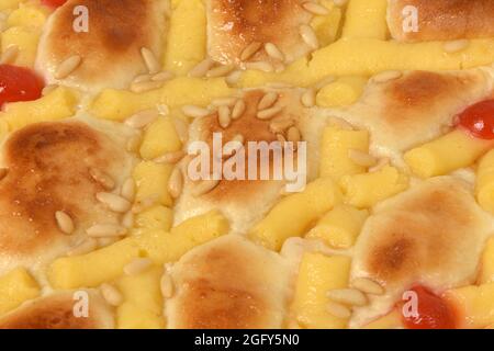 close up of sponge cake of egg cream, pine nuts and cherries on white background Stock Photo