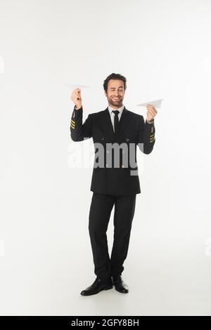 Smiling pilot holding paper planes on white background Stock Photo