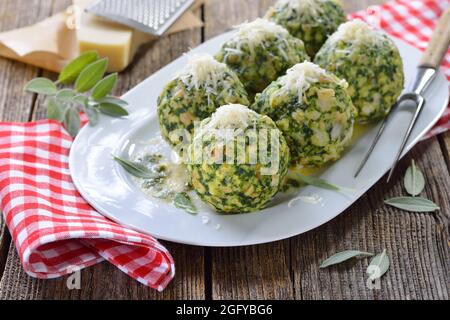 Homemade traditional South Tyrolean spinach dumplings made of white bread and fresh spinach leaves, served with melted sage butter and grated parmesan Stock Photo
