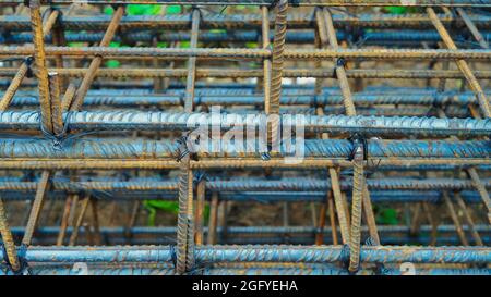 Rusty metal wiring is laid on the ground of house under construction. Preparation for making foundation of a building. Stock Photo