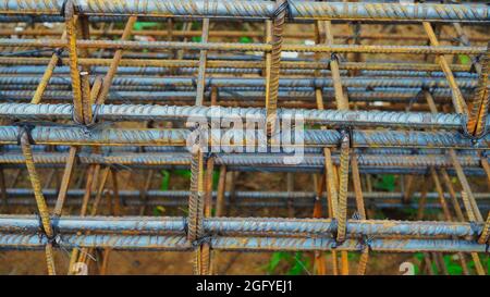 Modern house under construction waits for concrete slab pouring.Rusty metal wiring is laid on the ground of house under construction. Stock Photo