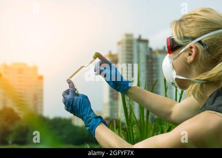 Woman with hands in gloves holds a glass with a sample of water. Sampling from open water Stock Photo