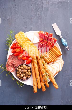 Charcuterie board with cheese, salami, mini tomatoes, olive oil and cracker Stock Photo