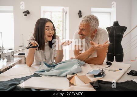 Positive interracial designers talking near fabric and color swatches Stock Photo