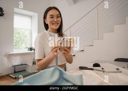 Asian designer smiling at camera while holding color swatches Stock Photo