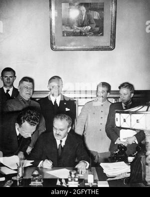 Soviet Foreign Minister Molotov signing the German-Soviet non-aggression pact (the Nazi-Soviet Pact or the Molotov-Ribbentrop Pact) with Joachim von Ribbentrop and Josef Stalin standing looking on. Stock Photo