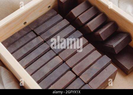 Handmade soap bars batch in wooden box. Deep brown color men solid soaps Stock Photo