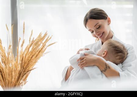 happy mother hugging toddler son sleeping in bathrobe Stock Photo