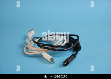 White and black wires with different usb interfaces on a blue background. Gadgets charging concept. Stock Photo