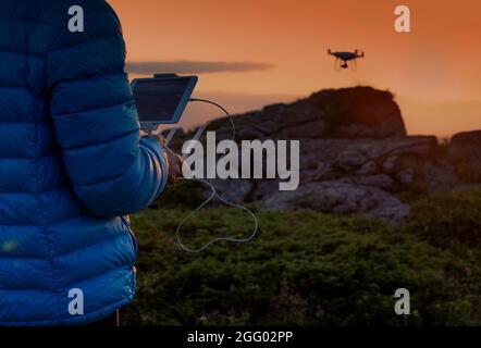 Close up of male's hands holding remote control and driving drone above rocks on mountain peak Stock Photo