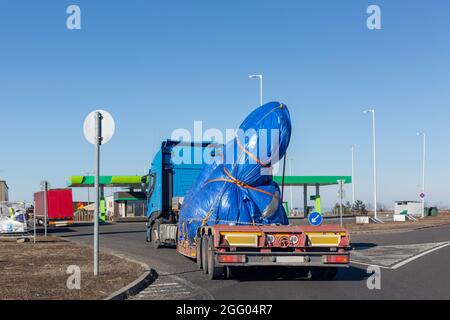 Blue truck with special semi-trailer for oversized loads transportation. Oversize load on flatbed trailer. Stock Photo
