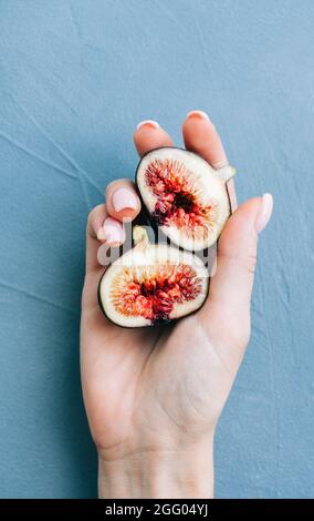 Fresh ripe figs in hand on blue background, close-up. Stock Photo