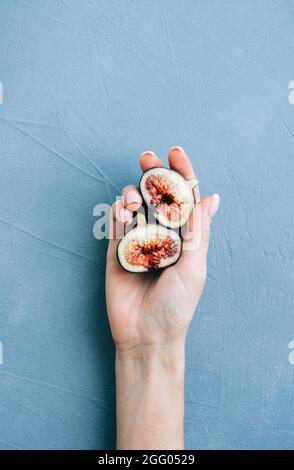 Fresh ripe figs in hand on blue background, close-up. Stock Photo