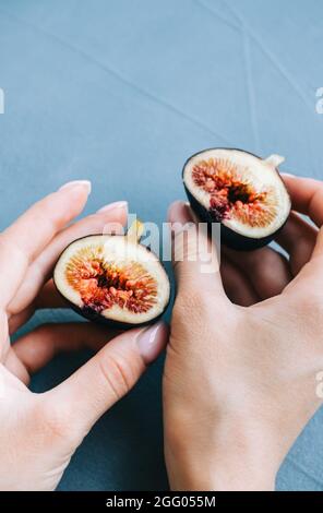 Fresh ripe figs in hand on blue background, close-up. Stock Photo