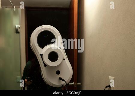 Woman with remote control in hand pointing towards window cleaning automat to send start order cleaning bathroom mirror in Mexico City Stock Photo