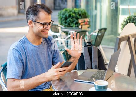 Young latin man video calling with computer outside. Stock Photo