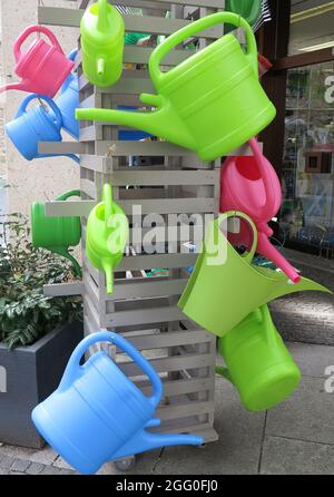 Collection of colorful plastic watering cans for sale Stock Photo