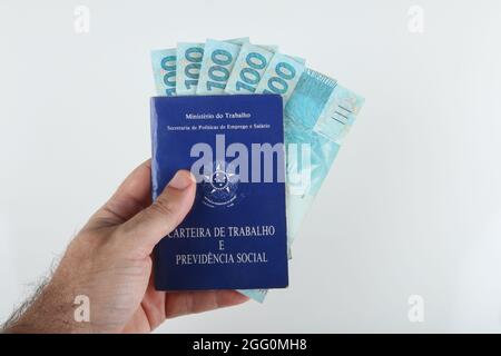 Bahia, Brazil. August 27, 2021. Brazilian work card and Brazilian money. TRANSLATION: Federative Republic of Brazil, Ministry of Labor. Work record bo Stock Photo