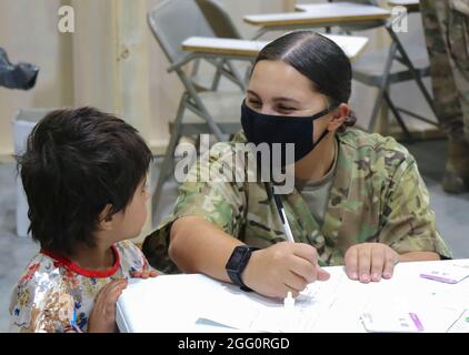 A U.S. Army National Guard Soldier assigned to Task Force Spartan, U.S. Army Central, assists an Afghan evacuee with a medical screening process as one of the first steps in his arrival at Camp Buehring, Kuwait, Aug. 25, 2021. USARCENT Soldiers from all components continue to work with their U.S. Central Command and Department of State teammates to support Afghanistan evacuation efforts with transportation, security, logistics and medical assistance at locations in Kuwait. (U.S. Army photo by Pfc. Katelynn Bissell) Stock Photo