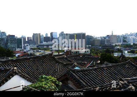 Modern Seoul as seen between the traditional rooftops of the Bukchon Hanok village. Seoul, South Korea. Stock Photo