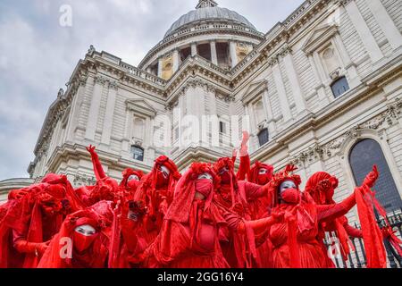 London, UK. 27th Aug, 2021. Extinction Rebellion's Red Rebel Brigade perform outside St Paul's Cathedral during the demonstration. Extinction Rebellion protesters staged the Blood Money March, part of their two-week Impossible Rebellion campaign, targeting the City of London, the capital's financial hub. (Photo by Vuk Valcic/SOPA Images/Sipa USA) Credit: Sipa USA/Alamy Live News Stock Photo